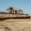 Scrapped ship, dismantled on a beach, the sea in the background.