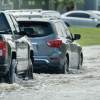 A series of cars battle flooding with high waters on the road.