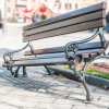 Broken wooden bench at San Francisco bus stop, a man walking away in the background.