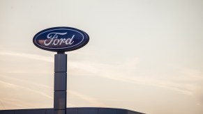 The ford logo on a sign outside a dealership which may offer an employee discount to everyone, sun setting in the background.