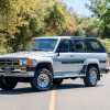 A light metallic 1986 Toyota 4Runner 22R-E parked in the middle of a two-lane road in left front angled view