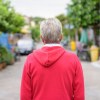 Suburban dad in red sweatshirt, watches street.