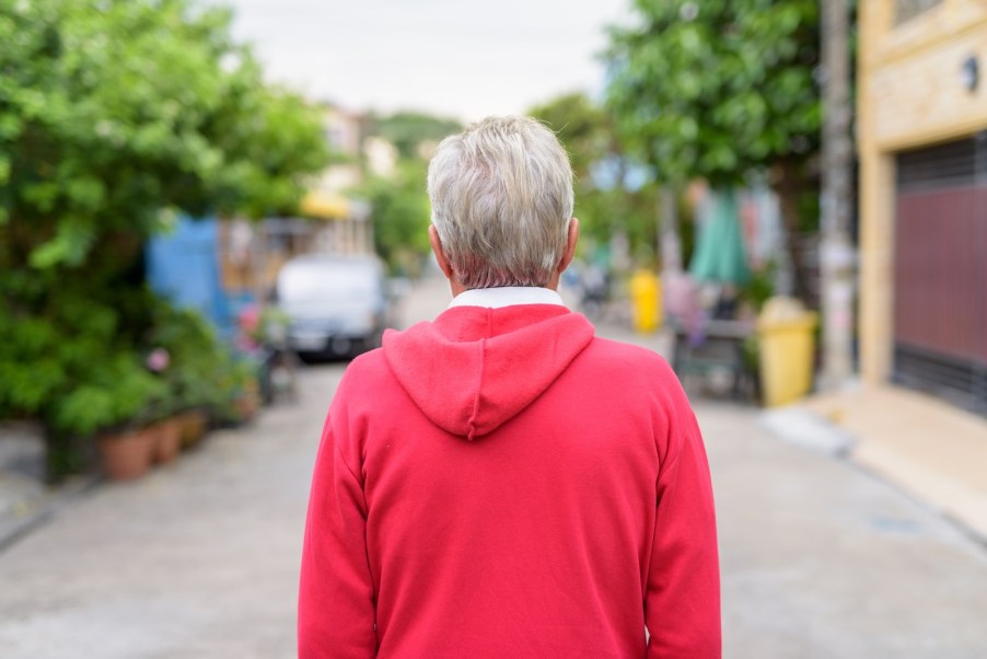 Suburban dad in red sweatshirt, watches street.